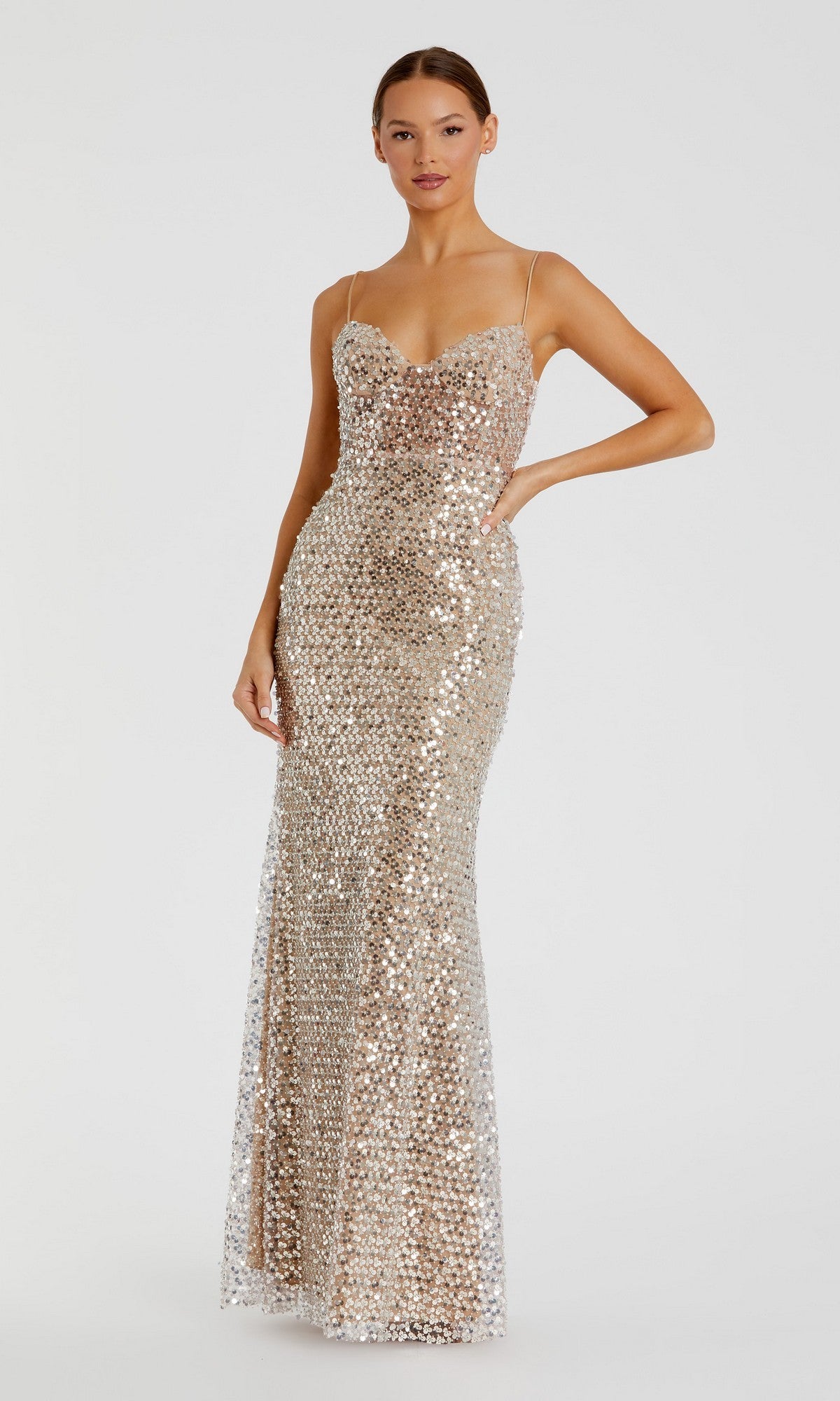 A woman stands against a plain light background wearing the Long Formal Dress: Mac Duggal 68895 in Nude, a floor-length, sleeveless evening gown featuring thin straps and a fitted silhouette embellished with silver sequins.